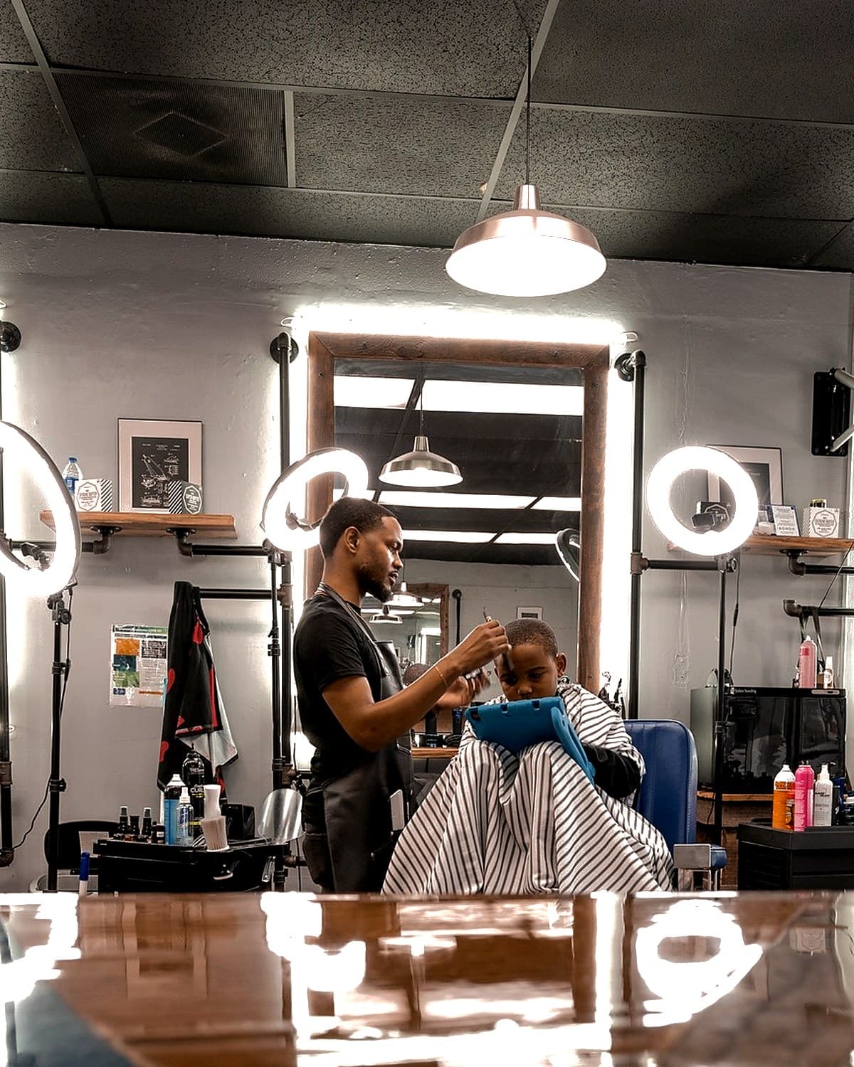 Kenneth Bell cutting a client at his wood-framed station under two ring lights at Vanzant Barbershop Lounge