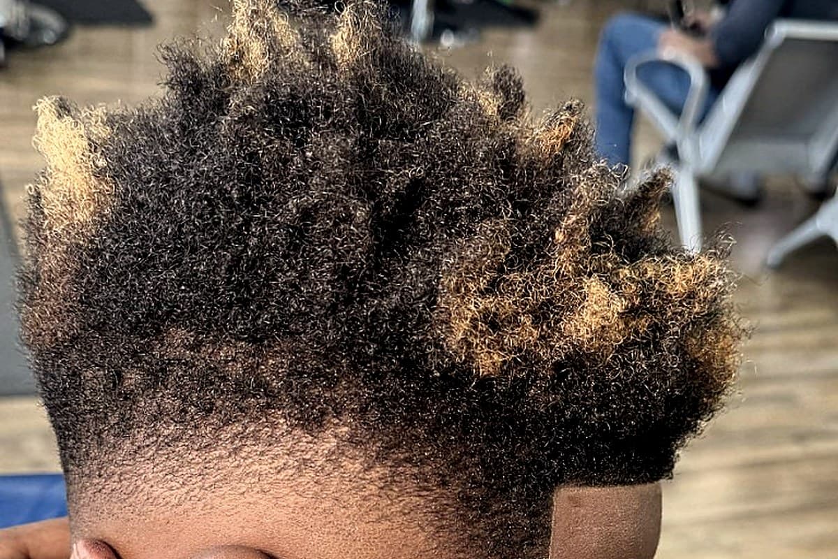 Kid's curly fade with blonde tips and a barber's steady hand at Vanzant Barbershop Lounge Kid's curly fade with blonde tips and a barber's steady hand at Vanzant Barbershop Lounge
