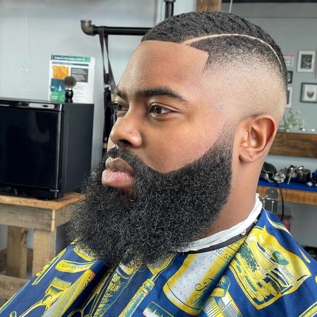 Skin fade with hard part, crisp lineup, and sculpted beard
