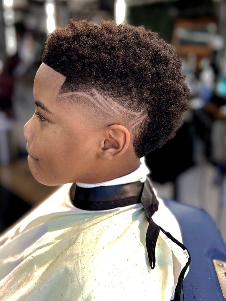 Kid's coiled top with skin fade, sharp lineup, and custom side design