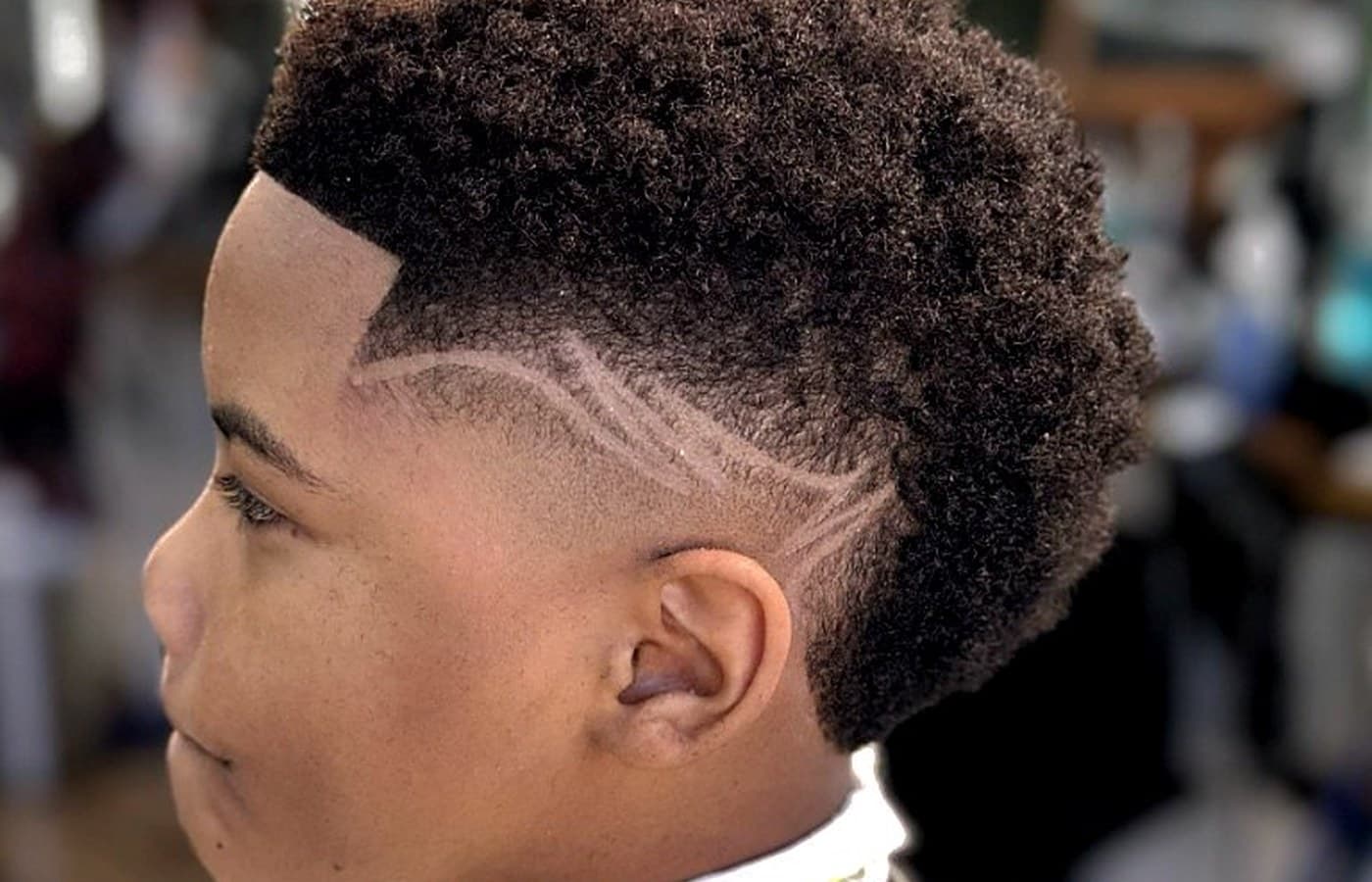 Kid's coiled top with skin fade and custom side design at Vanzant Barbershop Lounge