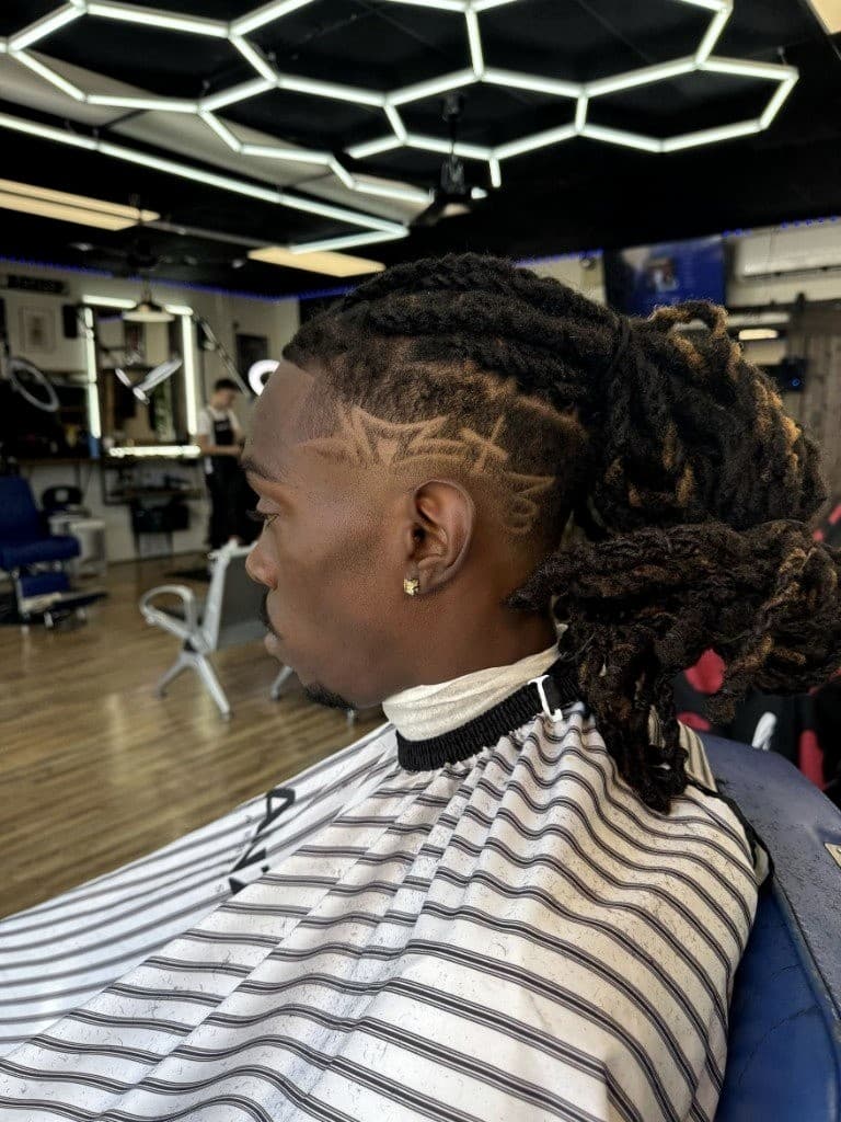 Lined-up locs with skin fade and custom design at Vanzant Barbershop Lounge Lined-up locs with skin fade and custom design at Vanzant Barbershop Lounge