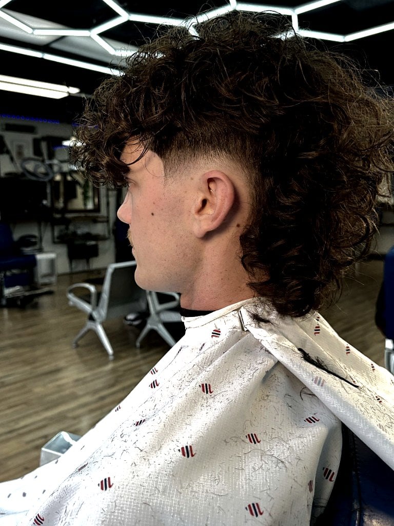 Curly burst-fade mullet with volume on top and length in back