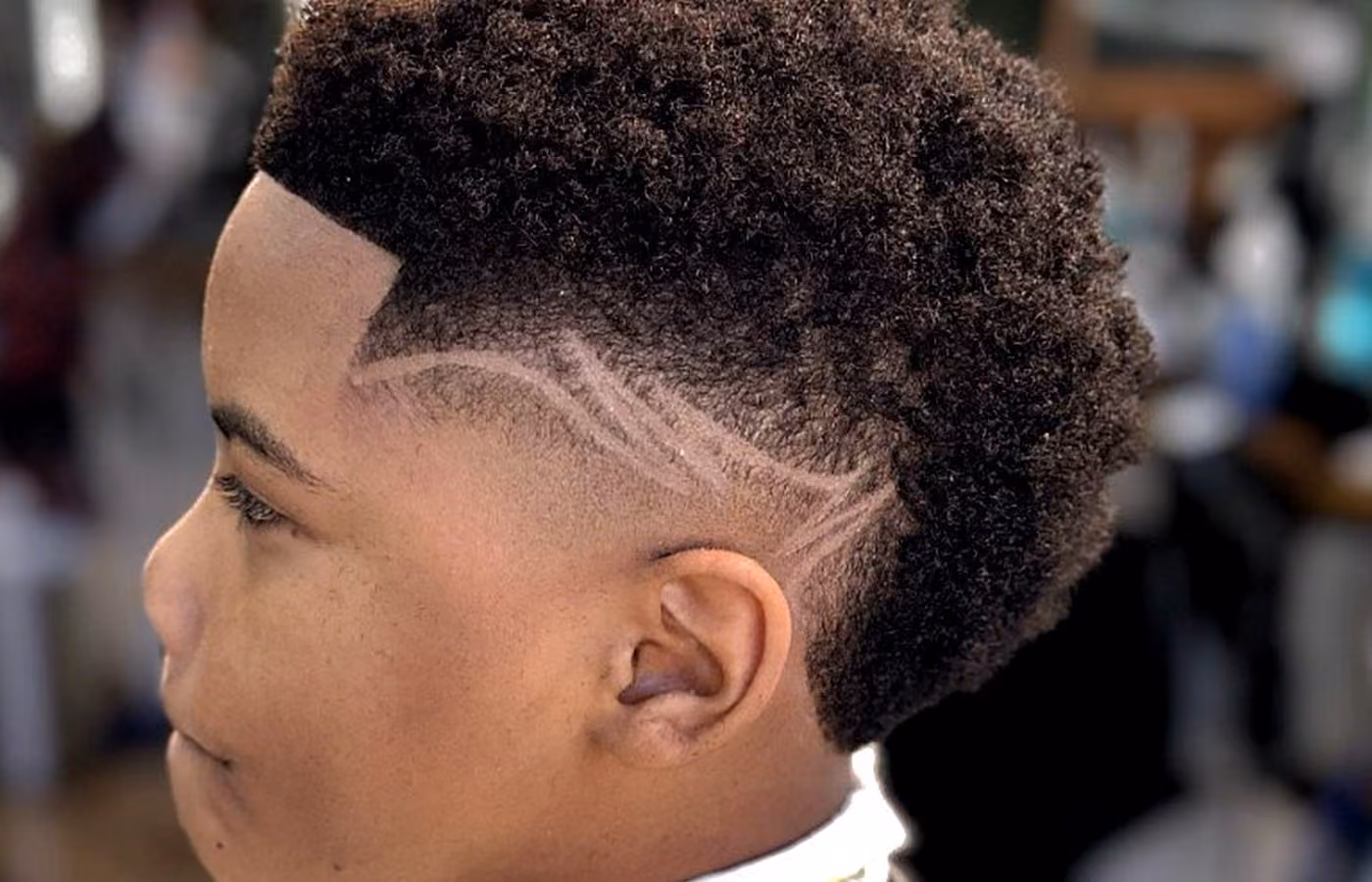 Kid's coiled top with skin fade and custom side design at Vanzant Barbershop Lounge