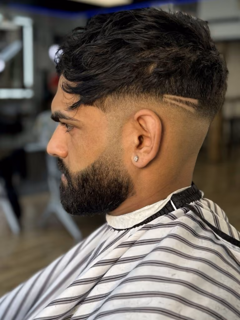 Skin fade with custom slash design and sculpted beard
