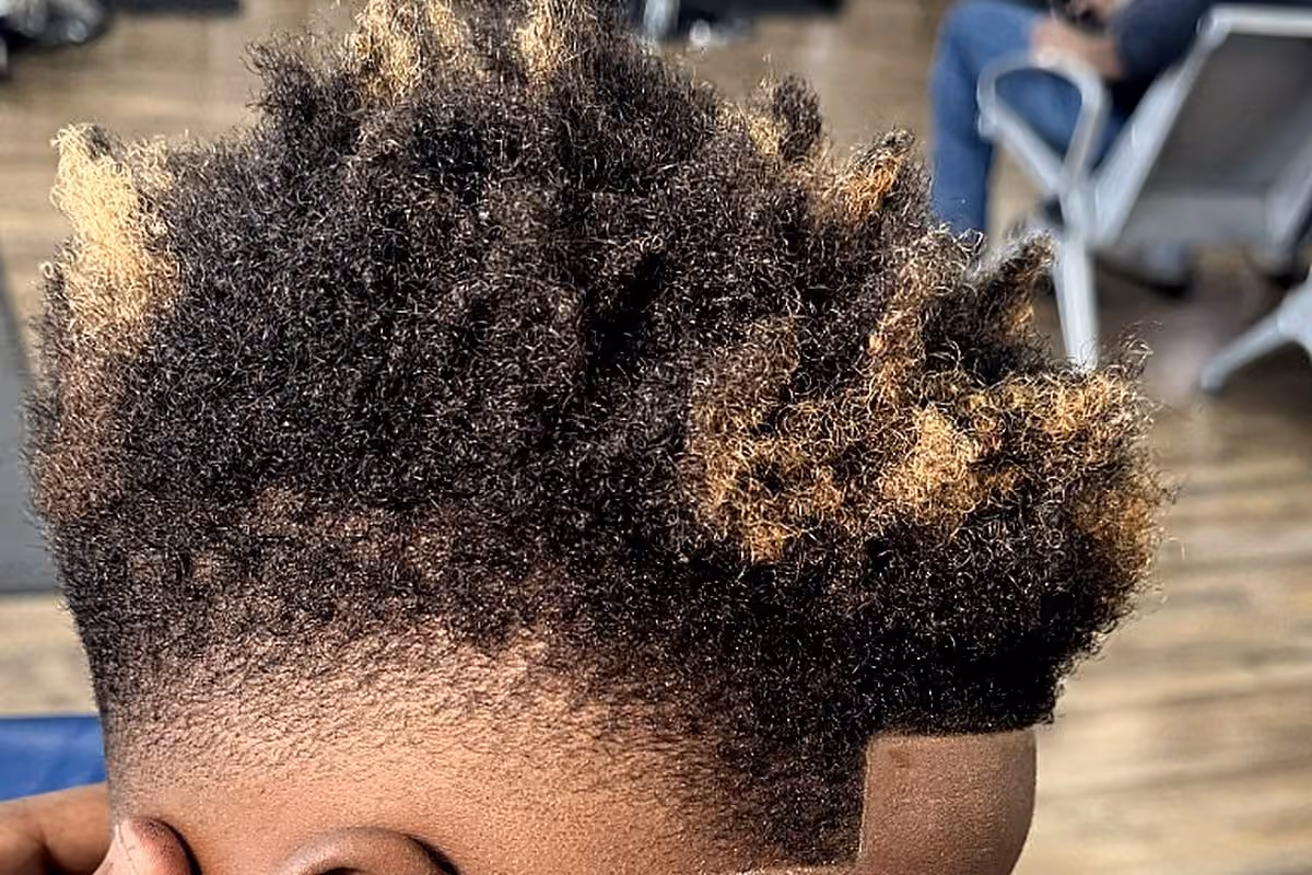 Kid's curly fade with blonde tips finished at Vanzant Barbershop Lounge