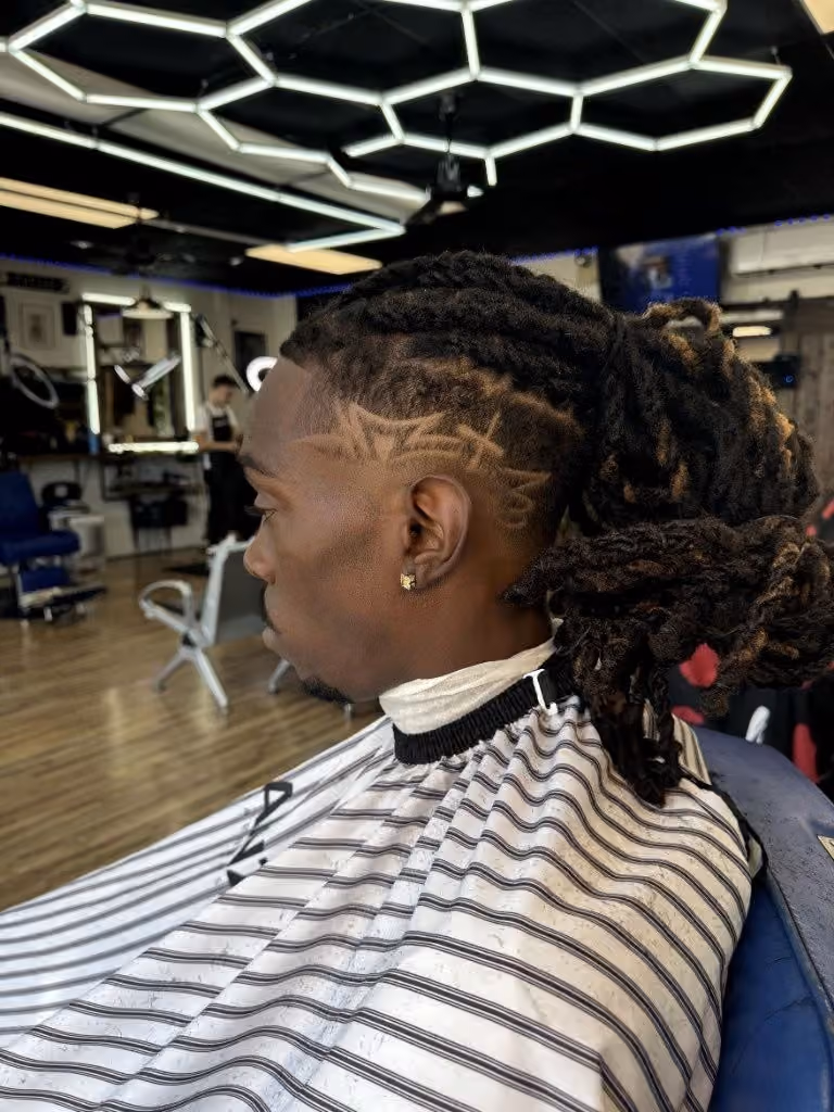 Lined-up locs with skin fade and custom design at Vanzant Barbershop Lounge Lined-up locs with skin fade and custom design at Vanzant Barbershop Lounge