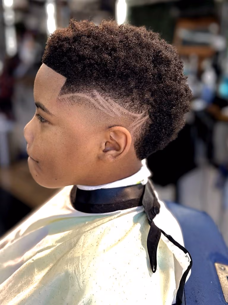 Kid's coiled top with skin fade, sharp lineup, and custom side design